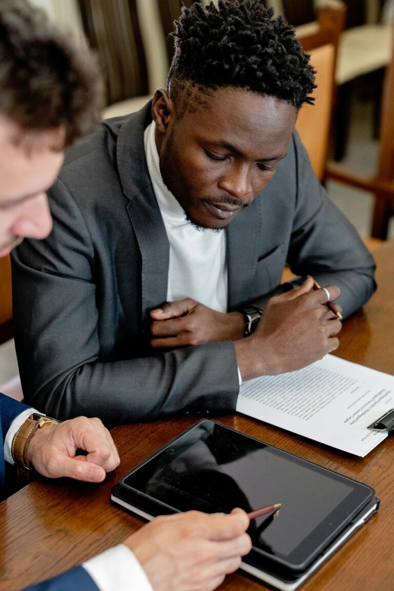 Professionals reviewing legal documents and using a tablet in a formal business setting.